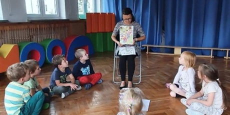 Powiększ grafikę: Nauczycielka czyta dzieciom opowiadanie i pokazuje obrazki.