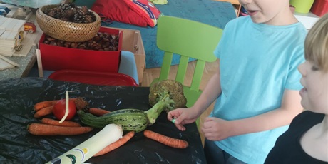 Powiększ grafikę: Dwoje dzieci tworzy postać z warzyw na stoliku.