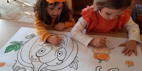 Powiększ grafikę: Dwójka dzieci koloruje wspólnie obrazek dyni.