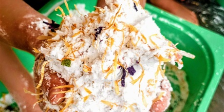 Powiększ grafikę: Dziecięce ręce trzymają masę z mąki i kawałków warzyw.