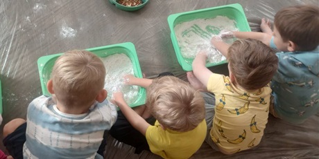 Powiększ grafikę: Czwórka dzieci miesza rączkami w pojemnikach wypełnionych mąką.