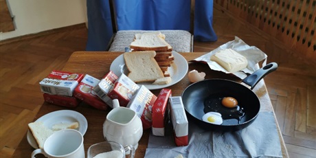 Powiększ grafikę: Na stole leżą produkty takie jak" jajka, chleb i masło.